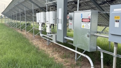 Image of backside of solar racking system with electrical and inverter box components. 