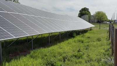 Perspective of solar array showing ample spacing between solar racking rows with green vegetation ground cover